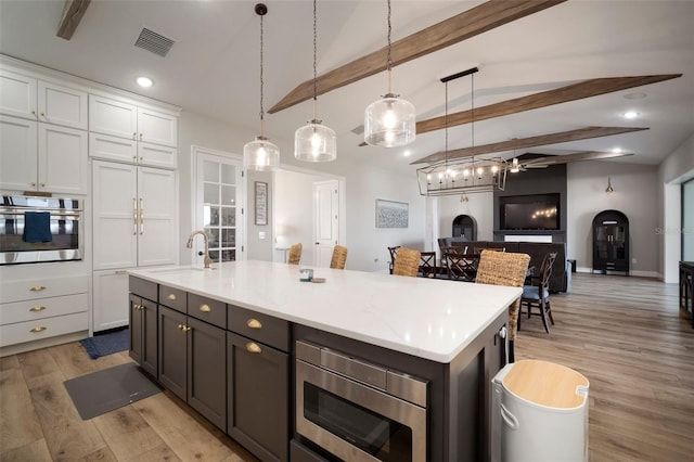 kitchen with appliances with stainless steel finishes, white cabinets, visible vents, and light wood-style flooring