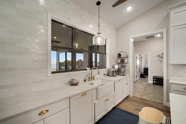 bathroom with wood finished floors, visible vents, a ceiling fan, vaulted ceiling, and backsplash