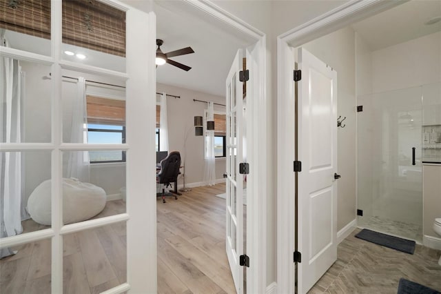 hallway with baseboards, a barn door, and light wood-style floors