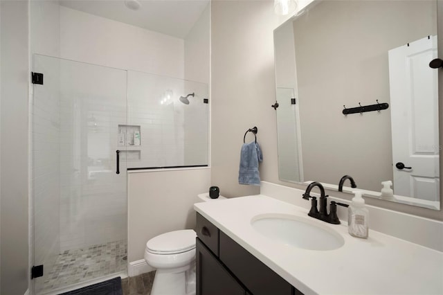 bathroom with a shower stall, toilet, and vanity