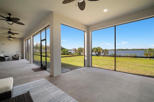 unfurnished sunroom featuring a ceiling fan and a water view