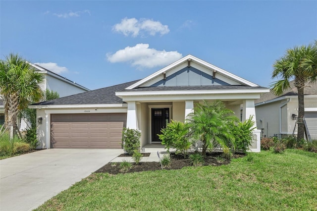 view of front of property with concrete driveway, stucco siding, an attached garage, board and batten siding, and a front yard