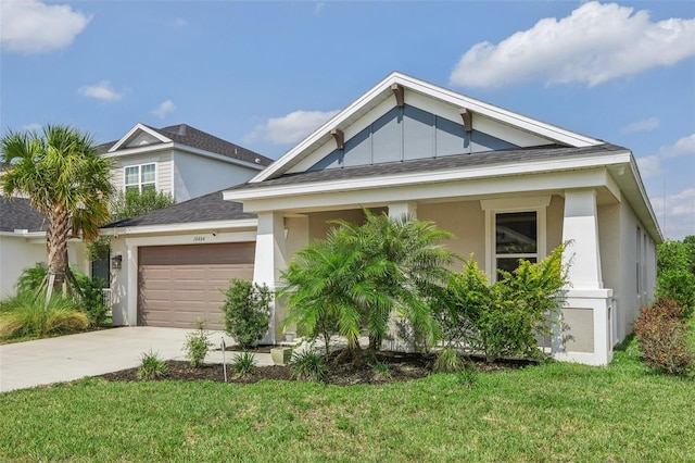 view of front of home with a garage, driveway, a front lawn, and stucco siding