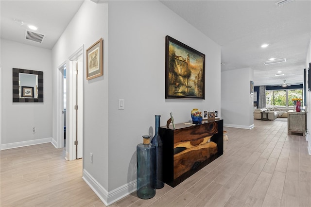 corridor featuring light wood-type flooring, visible vents, and baseboards