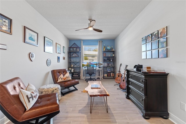 sitting room with a textured ceiling, wood finish floors, a ceiling fan, and baseboards