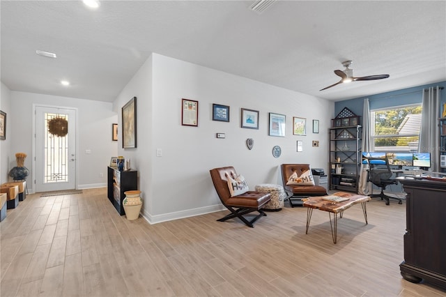 sitting room with light wood-style floors, visible vents, baseboards, and a ceiling fan