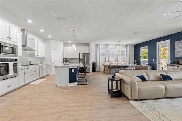 living area with light wood-style floors, a textured ceiling, a notable chandelier, and recessed lighting