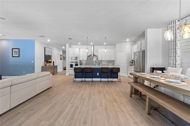 living room featuring light wood-style floors, recessed lighting, a textured ceiling, and baseboards