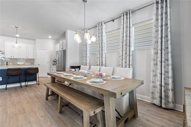 dining area with light wood-type flooring, a notable chandelier, baseboards, and recessed lighting