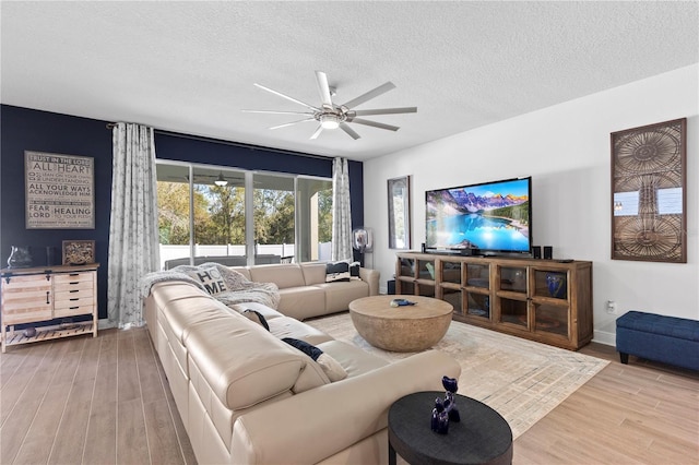 living area with ceiling fan, a textured ceiling, baseboards, and wood finished floors