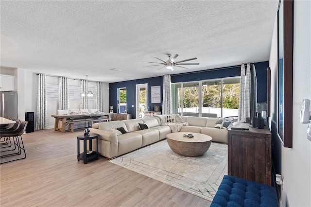 living area featuring ceiling fan, a textured ceiling, and light wood-style floors