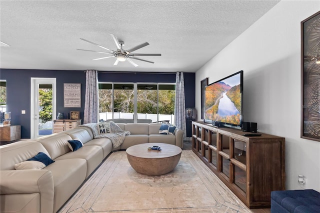 living room with ceiling fan, visible vents, and a textured ceiling