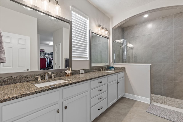 bathroom with double vanity, walk in shower, a sink, and a walk in closet