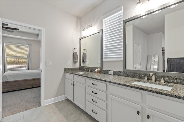 full bath featuring double vanity, tile patterned flooring, a sink, and baseboards