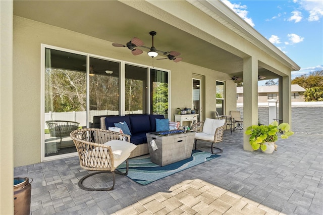 view of patio / terrace with fence, a ceiling fan, and an outdoor living space with a fire pit