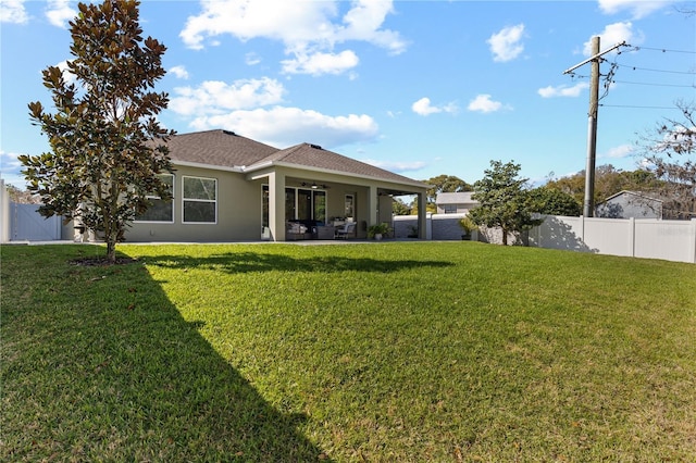 back of house featuring a fenced backyard, a lawn, a patio, and stucco siding