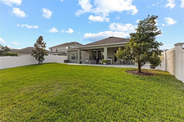 rear view of property featuring ceiling fan, a yard, a patio area, and a fenced backyard