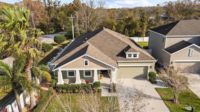 view of front facade featuring a porch, a garage, a shingled roof, fence, and driveway