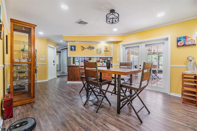 dining area with a textured ceiling, dark wood-style flooring, visible vents, french doors, and crown molding