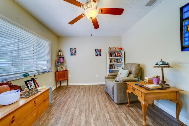 sitting room featuring baseboards, visible vents, ceiling fan, wood finished floors, and a textured ceiling