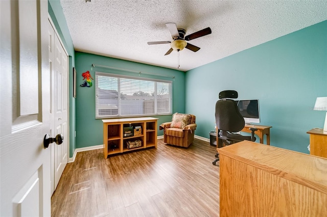 home office with a ceiling fan, a textured ceiling, baseboards, and wood finished floors