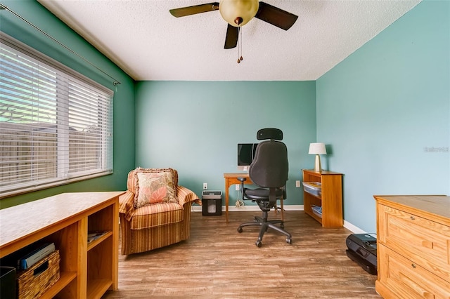 home office featuring a textured ceiling, ceiling fan, wood finished floors, and baseboards