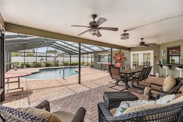 view of pool with glass enclosure, an outdoor living space, a ceiling fan, french doors, and a patio area