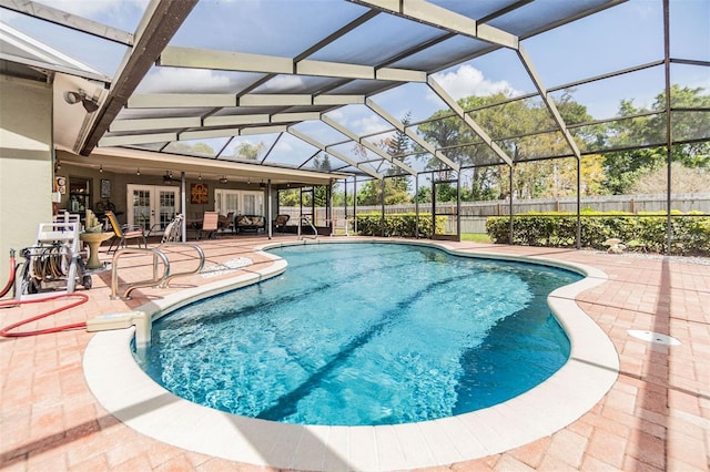 view of swimming pool with glass enclosure, french doors, a fenced backyard, and a patio