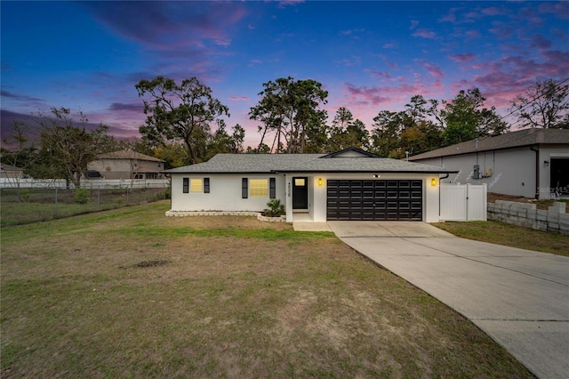 view of front facade featuring a garage, fence, concrete driveway, and a front yard