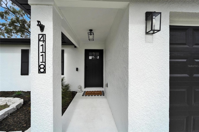 entrance to property featuring a garage and stucco siding