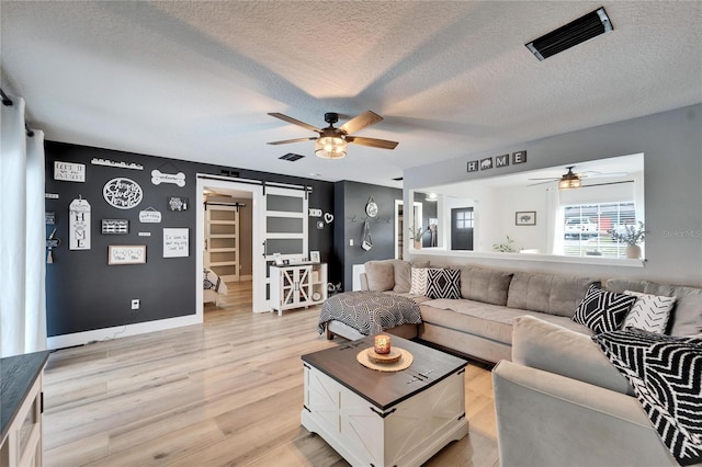 4118 Ramona Dr, Spring Hill, FL 34606 - living area with a ceiling fan, a barn door, a textured ceiling, and light wood-type flooring
