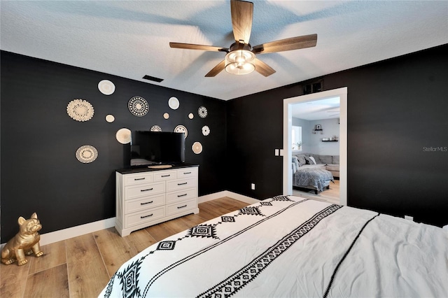 4118 Ramona Dr, Spring Hill, FL 34606 - bedroom with an accent wall, light wood-style flooring, a ceiling fan, and a textured ceiling