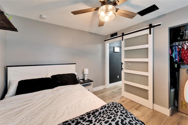 4118 Ramona Dr, Spring Hill, FL 34606 - bedroom featuring a barn door, light wood-style floors, and a ceiling fan