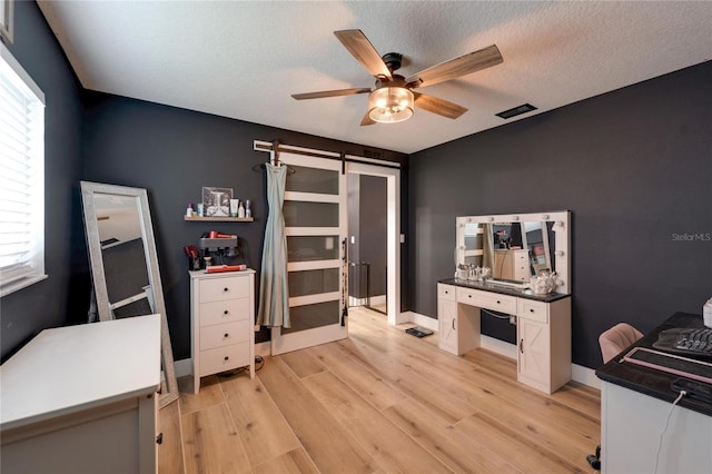 4118 Ramona Dr, Spring Hill, FL 34606 - office area featuring a barn door, ceiling fan, light wood finished floors, and a textured ceiling