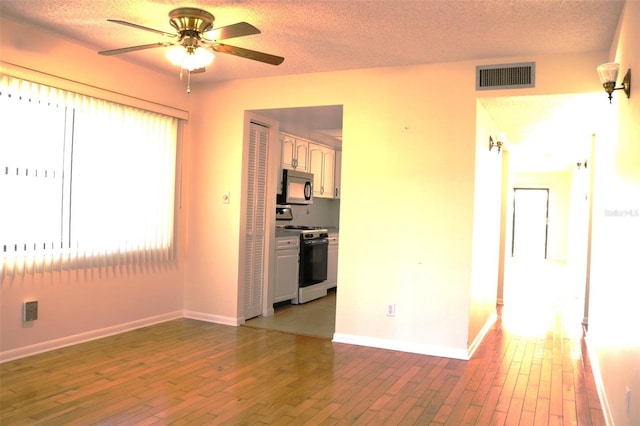 empty room with visible vents, baseboards, a ceiling fan, and hardwood / wood-style flooring