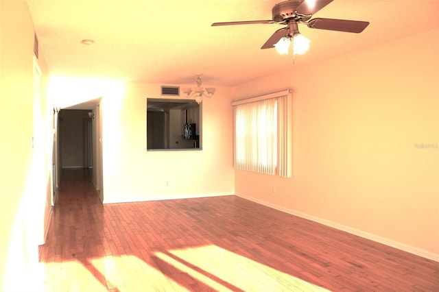 empty room with visible vents, a ceiling fan, baseboards, and wood finished floors