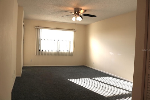 spare room with a ceiling fan, baseboards, a textured ceiling, and dark carpet