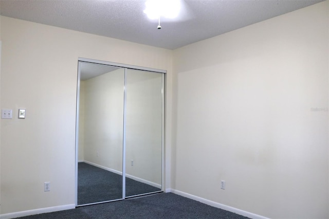 unfurnished bedroom featuring baseboards, a closet, and dark carpet