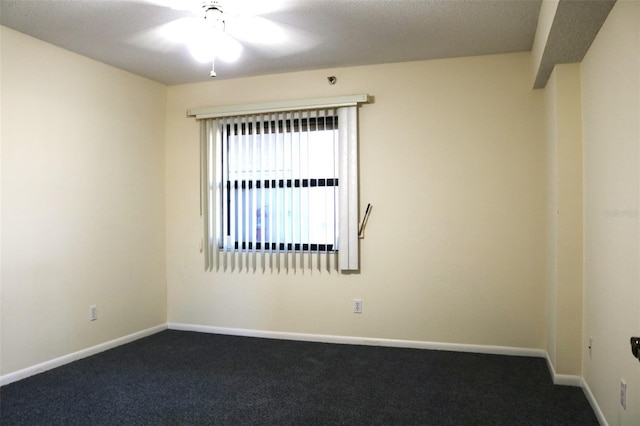 empty room featuring dark colored carpet and baseboards