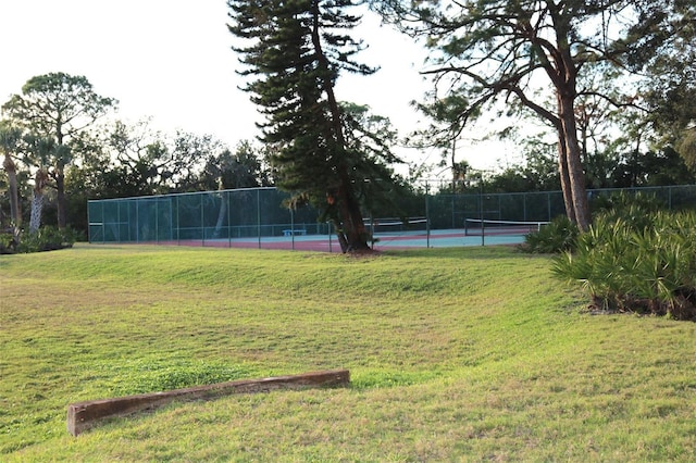 view of tennis court featuring a yard and fence