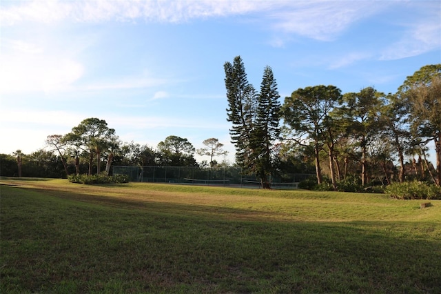 view of yard featuring a tennis court and fence