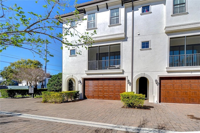 multi unit property featuring a garage, decorative driveway, and stucco siding