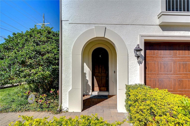 doorway to property featuring a garage and stucco siding