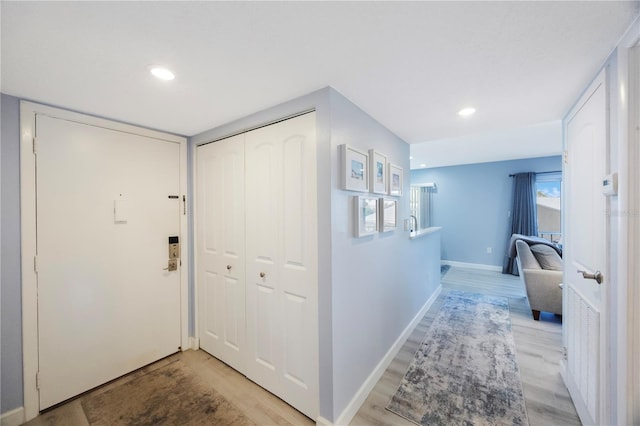 hall with light wood finished floors, baseboards, and recessed lighting