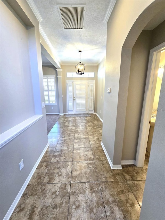 doorway with visible vents, crown molding, a textured ceiling, and baseboards