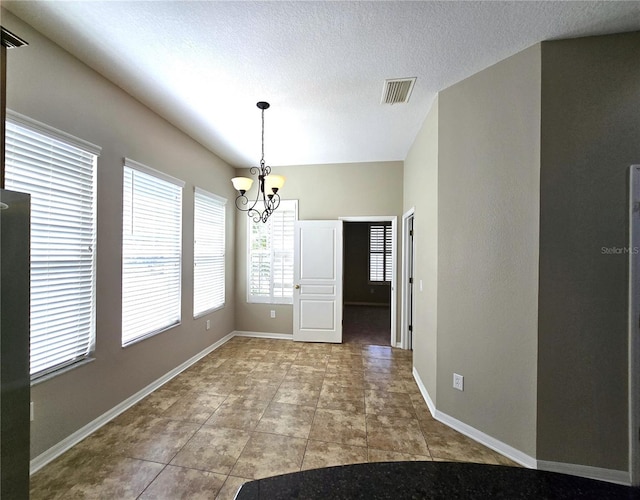 unfurnished dining area featuring visible vents, a textured ceiling, a chandelier, baseboards, and tile patterned floors