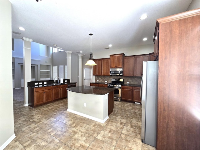 kitchen with decorative backsplash, dark countertops, appliances with stainless steel finishes, ornate columns, and a sink