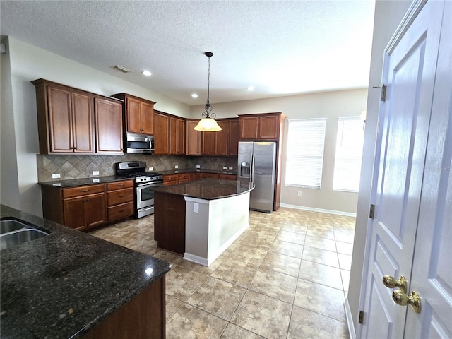 kitchen featuring stainless steel appliances, visible vents, decorative backsplash, a center island, and pendant lighting