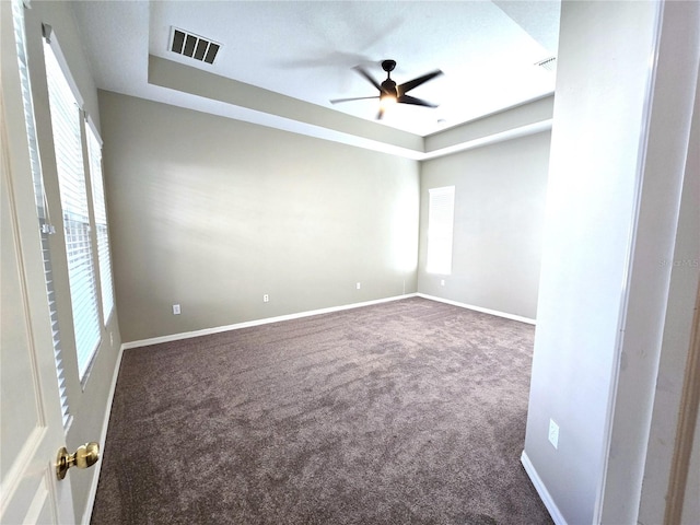 carpeted spare room featuring a ceiling fan, visible vents, and baseboards