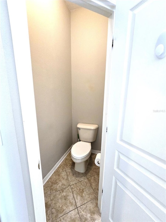 bathroom with toilet, baseboards, and tile patterned floors